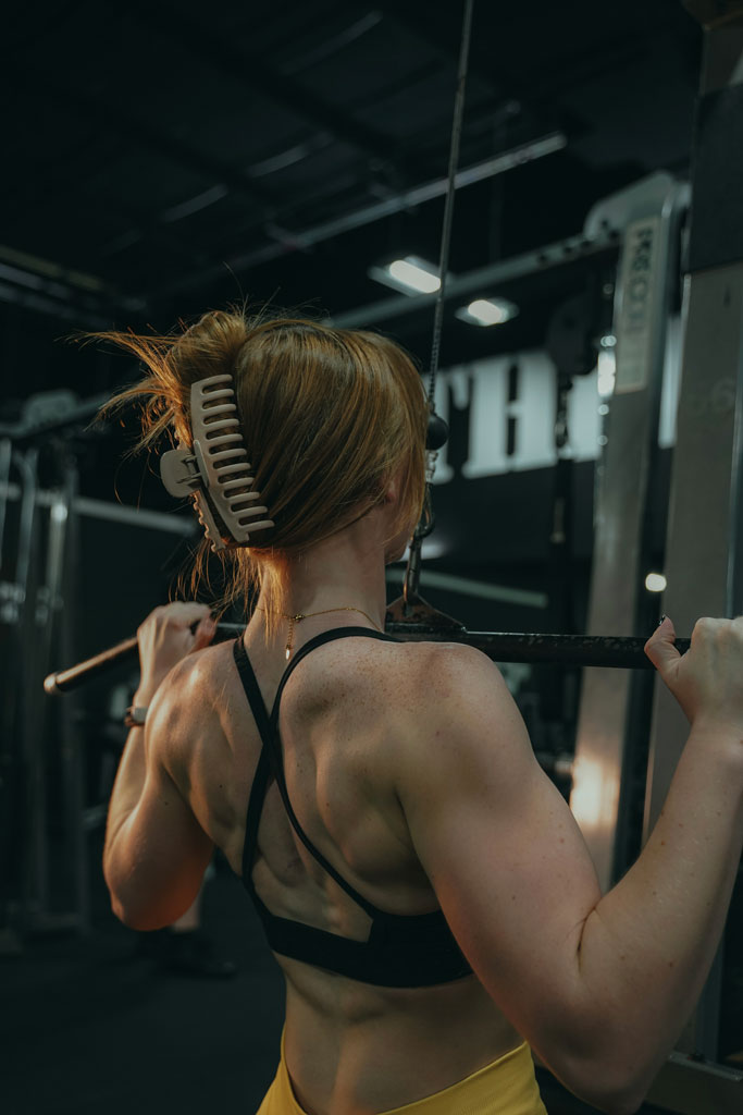 Coach is doing pull ups and showing her shoulders muscles.